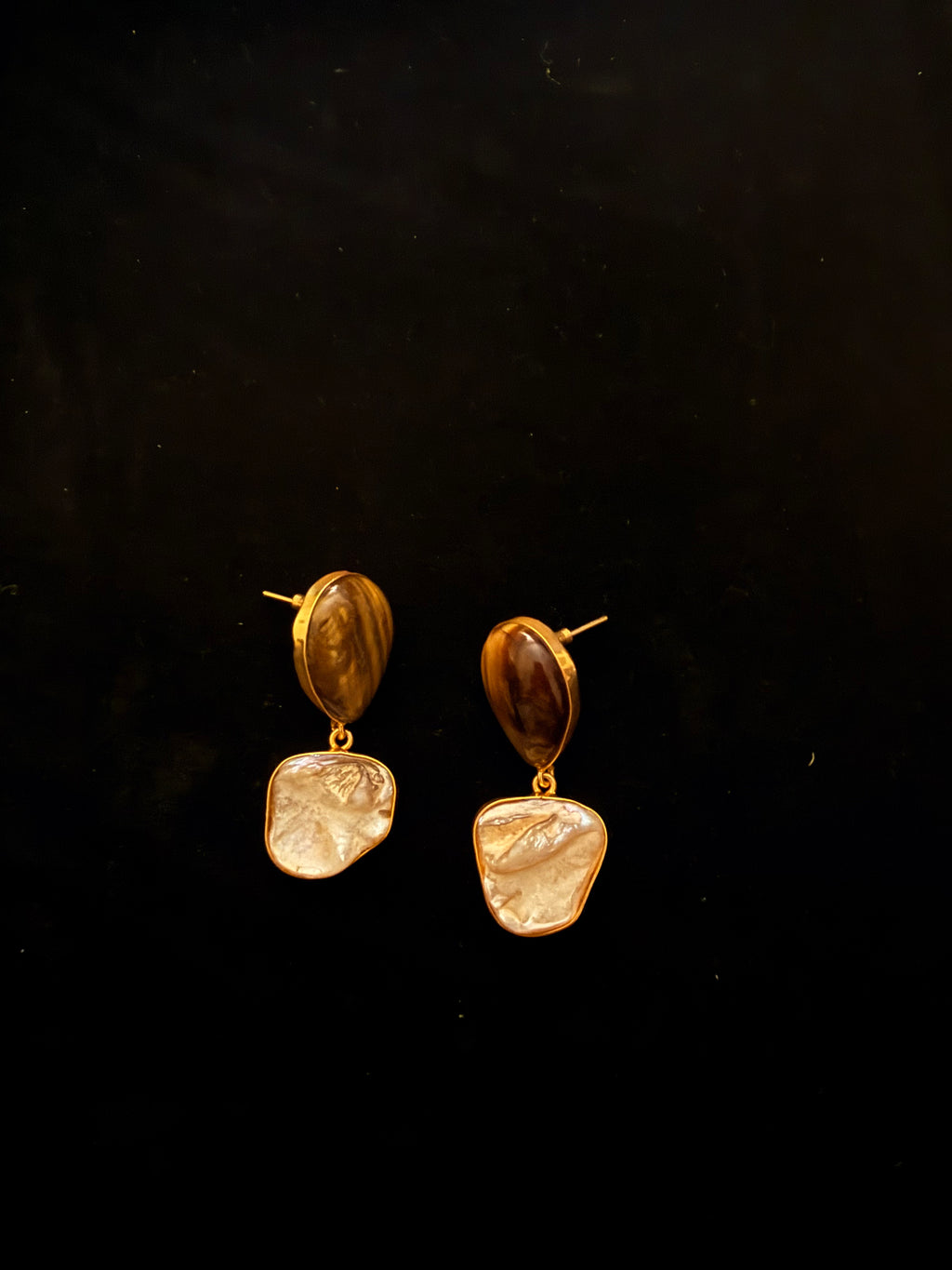 Pair of gold and brown earrings on a black background