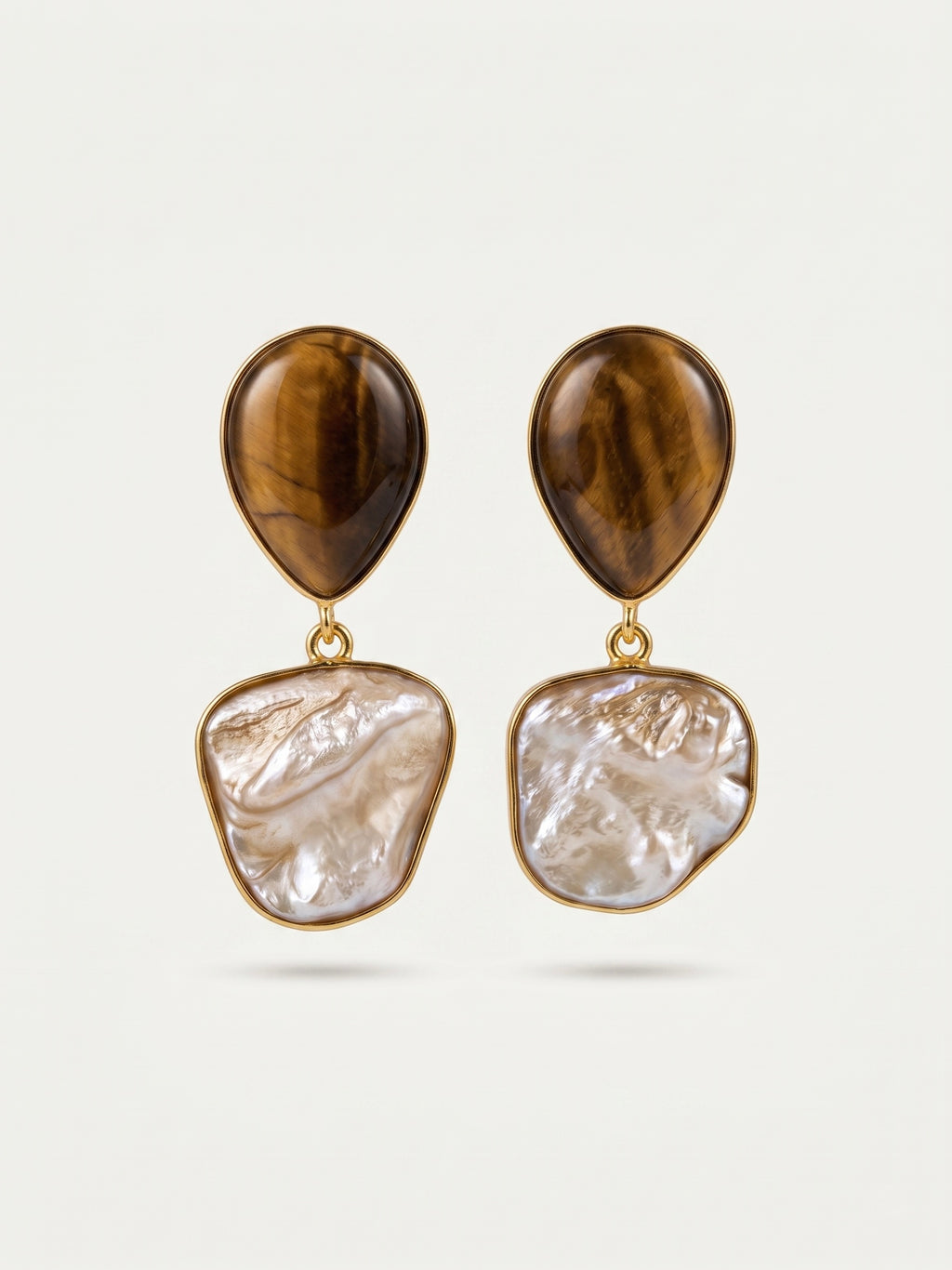 Pair of earrings with brown and white stone designs on a light gray background