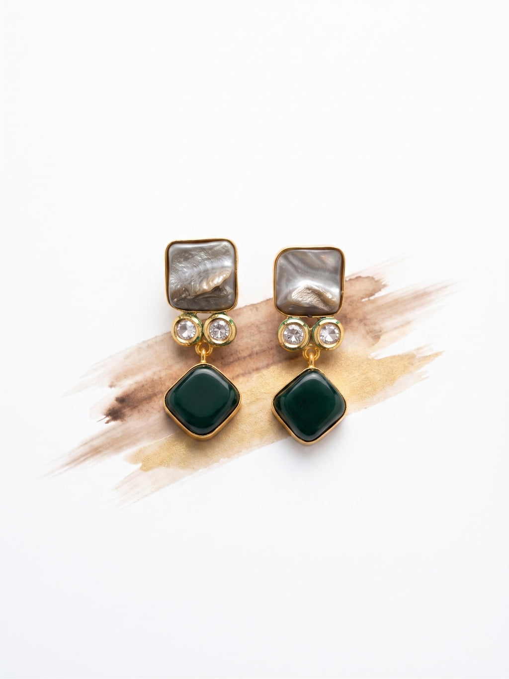 Pair of earrings with green gemstones and gold accents on a white background