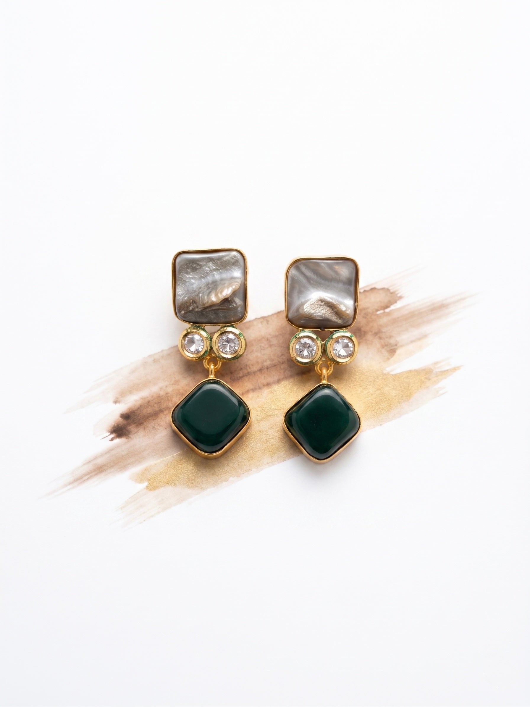 Pair of earrings with green gemstones and gold accents on a white background